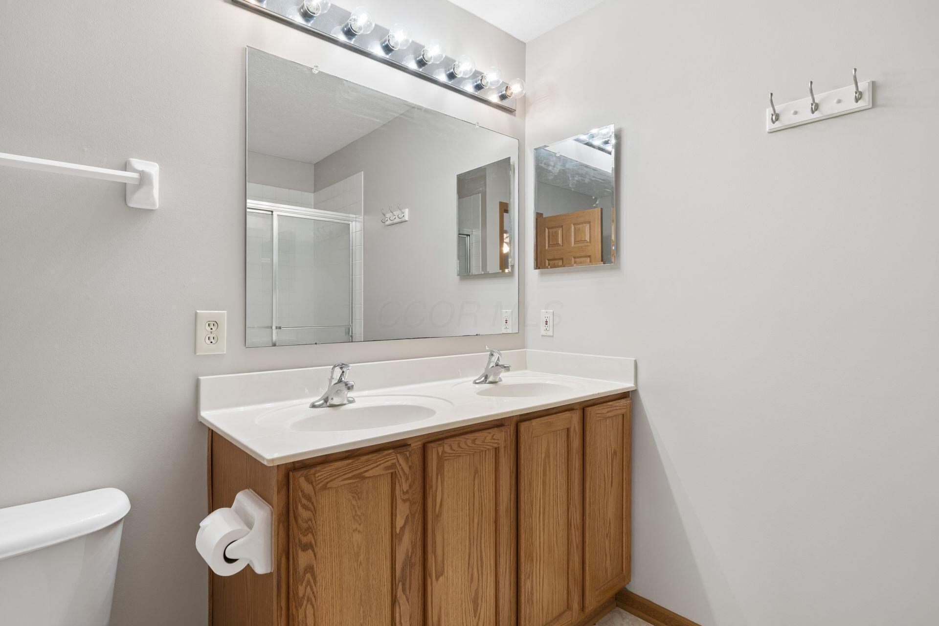 Bathroom with a double-sink oak vanity and large mirror.