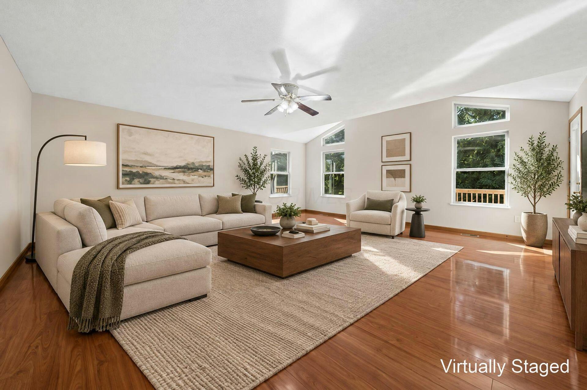 Living room with a cream sectional, wood coffee table, hardwood floors, and tall windows.