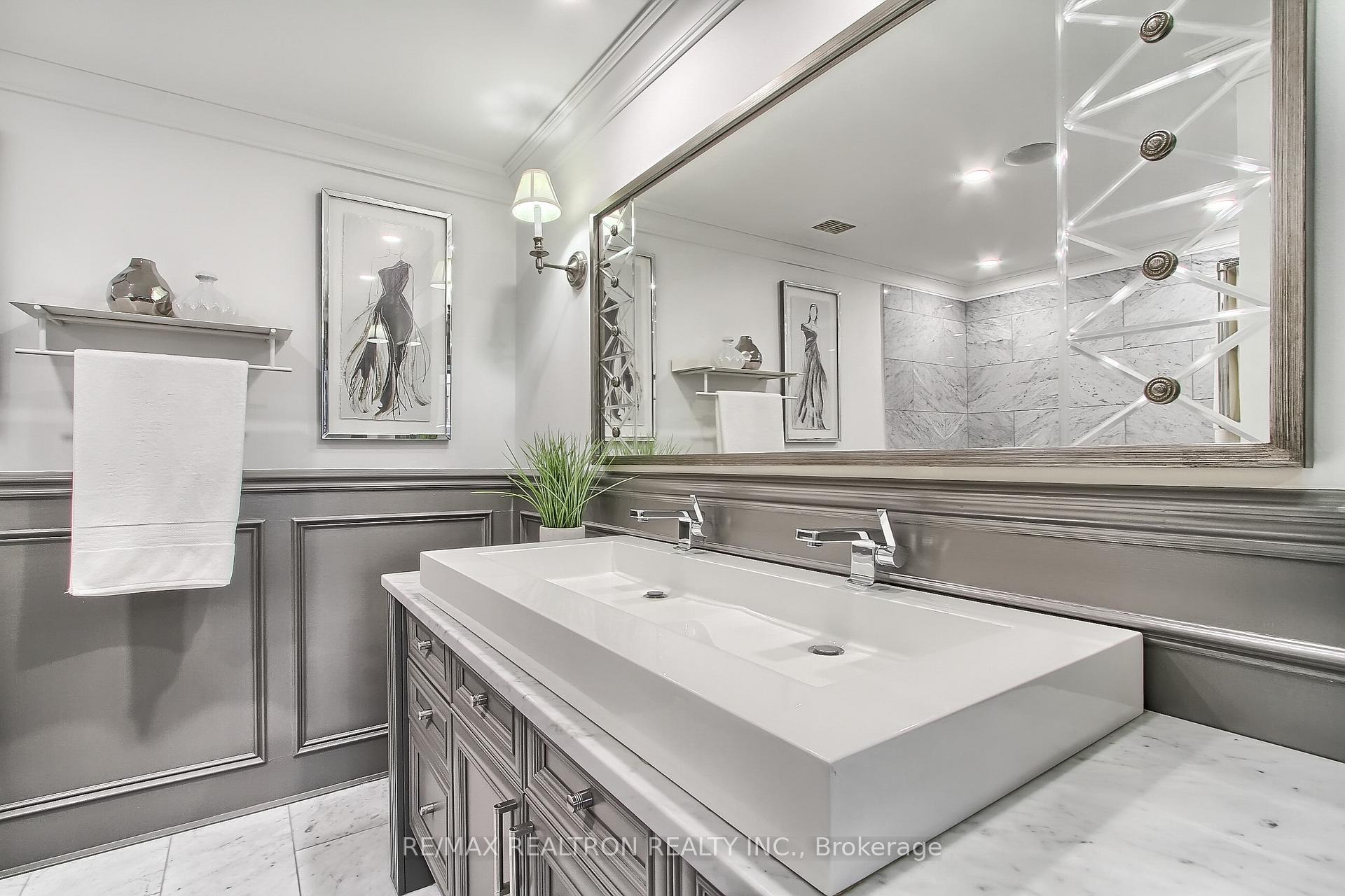 Bathroom with a white double sink, gray paneled vanity, marble surfaces, and a large mirror.