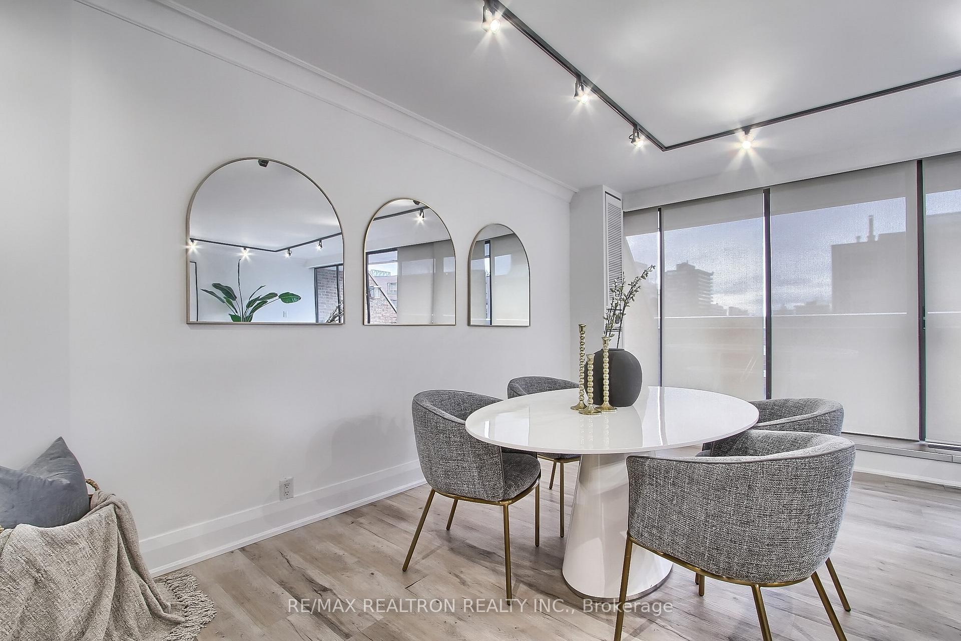 Condominium dining area with a white oval table, gray chairs, arched mirrors, and floor-to-ceiling windows.