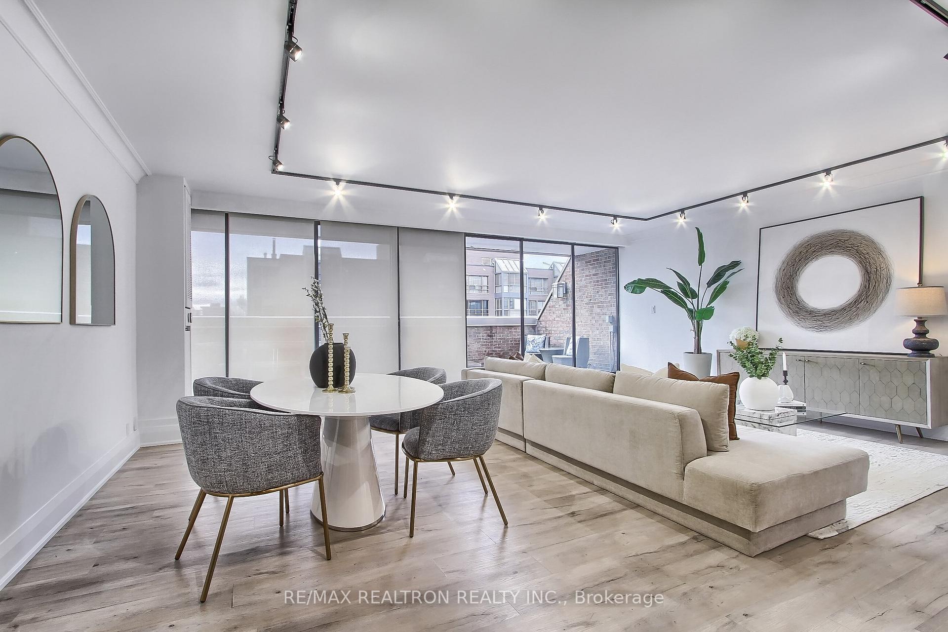 Open-plan condo living and dining room with a beige sectional, round table, and balcony windows.