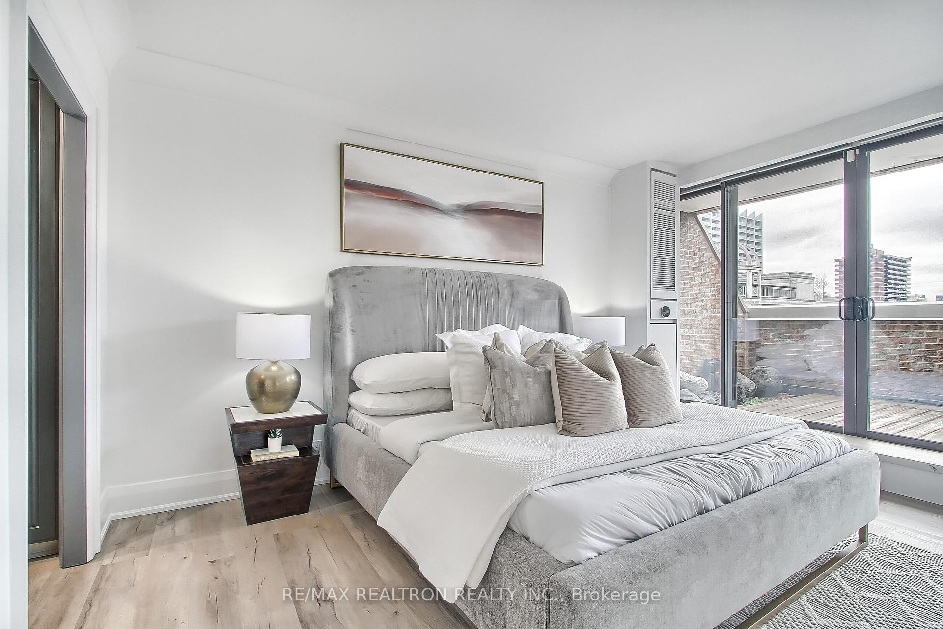 Staged bedroom with a gray upholstered bed beside sliding doors to a terrace.