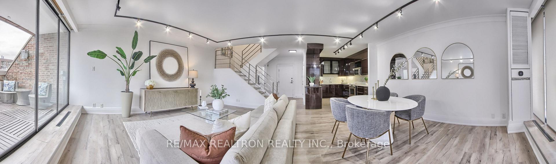 Open-plan condo living and dining area with a staircase, modern kitchen, and sliding doors to a balcony.