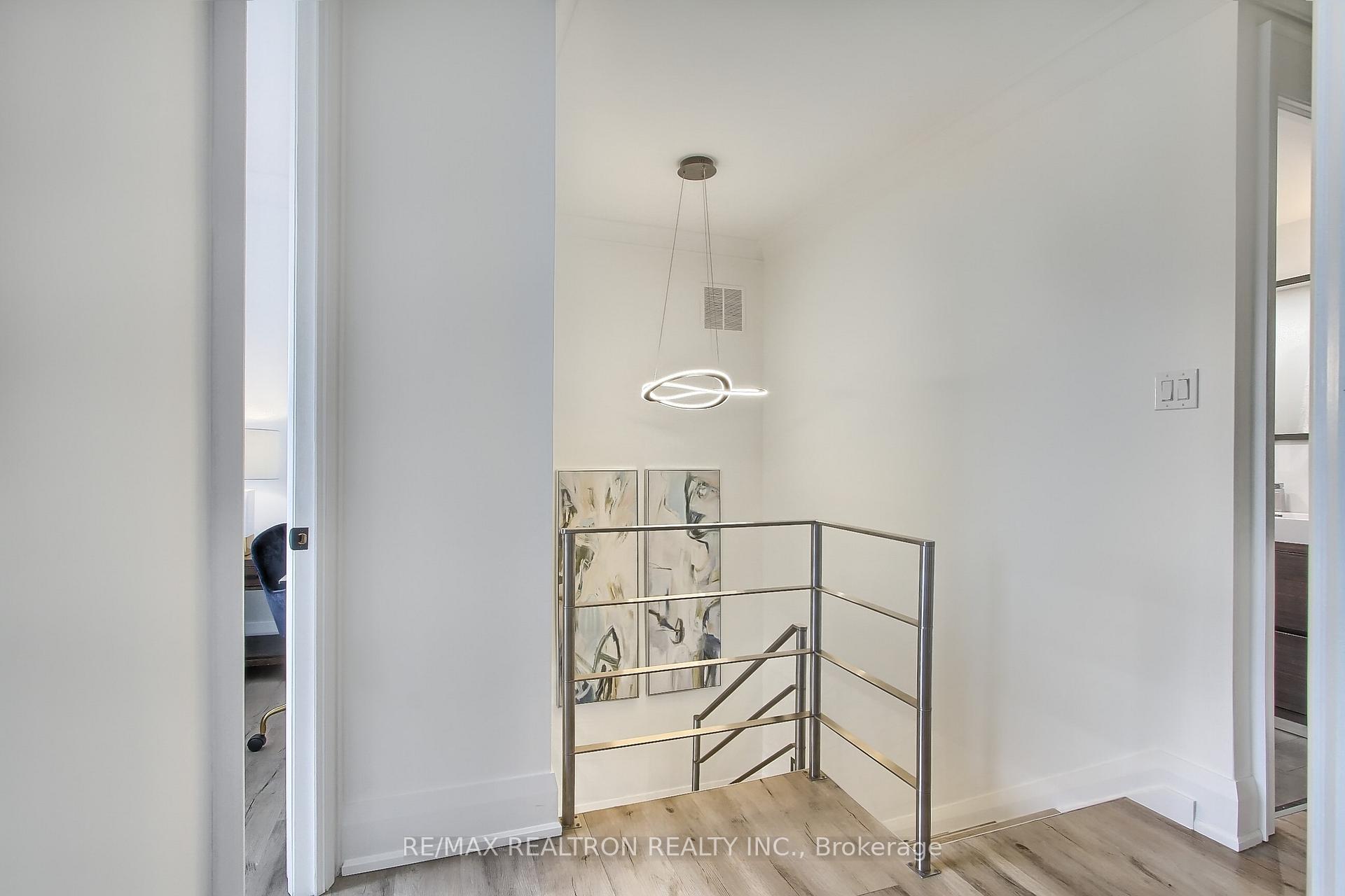 Modern stair landing with a metal railing, abstract artwork, and sculptural pendant light.