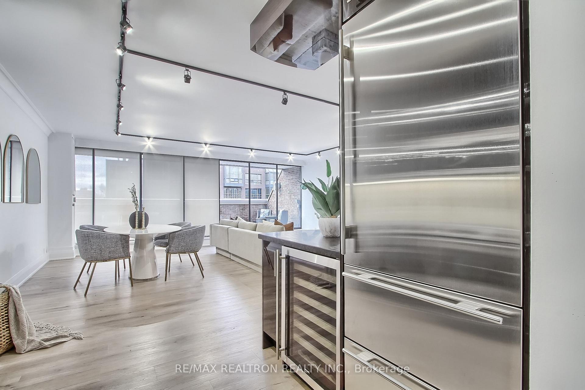 Open-plan condo dining and living area with a round table, pale sofa, and stainless-steel appliances.
