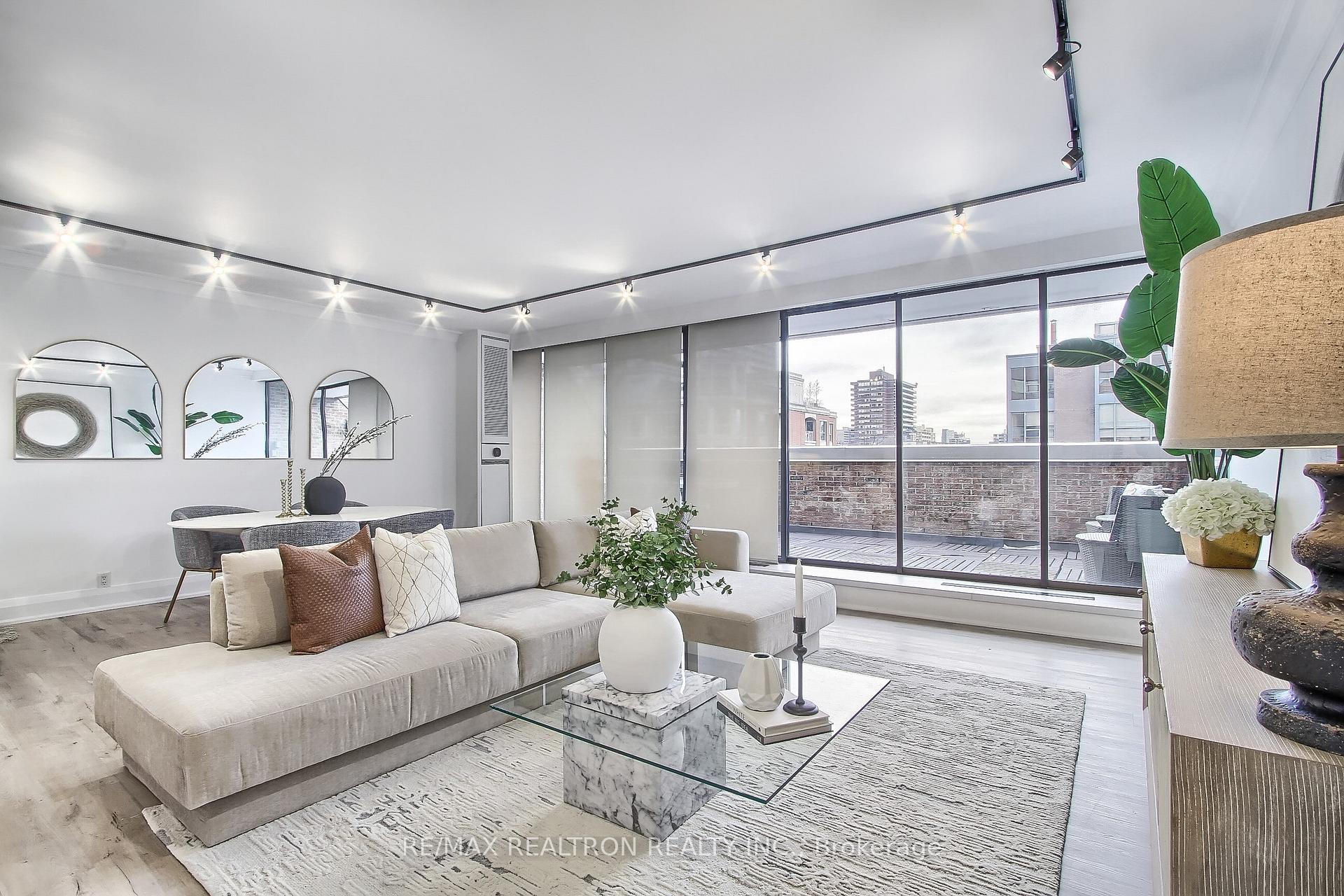 Staged condo living room with a cream sectional, dining area, and sliding doors opening onto a balcony.