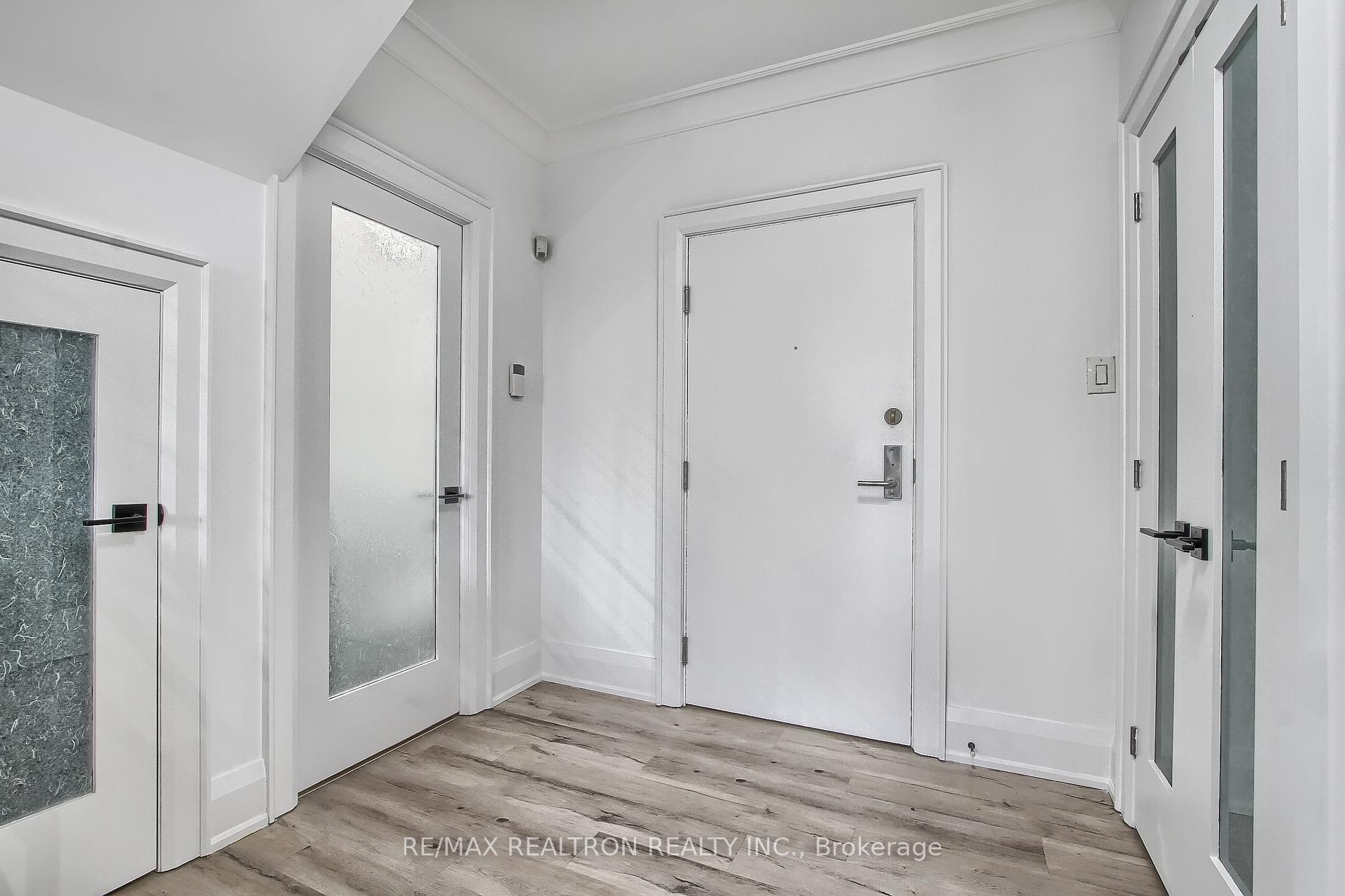 Apartment entry foyer with frosted-glass doors and gray-brown plank flooring.