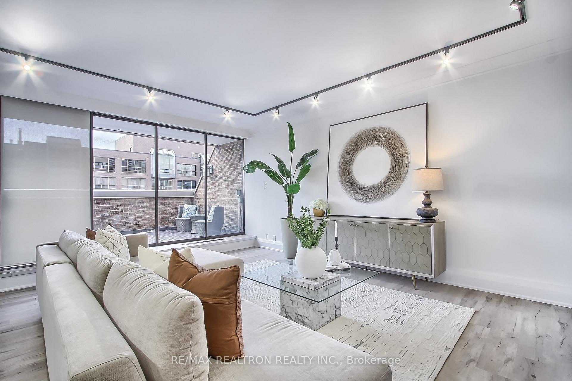 Staged condo living room with a white sectional and large windows opening onto a private terrace.