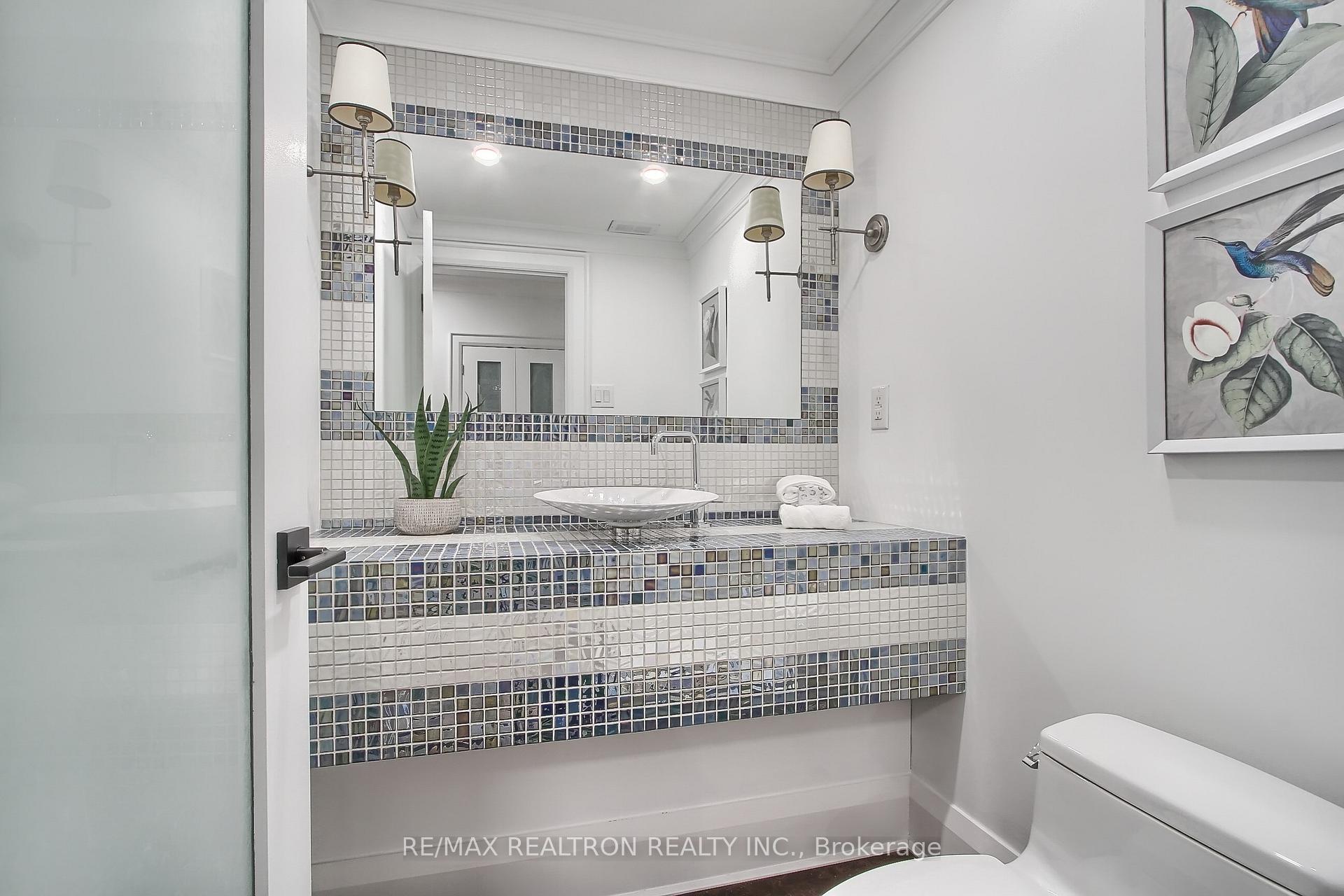 Bathroom with a mosaic-tiled vanity, vessel sink, large mirror and glass shower.
