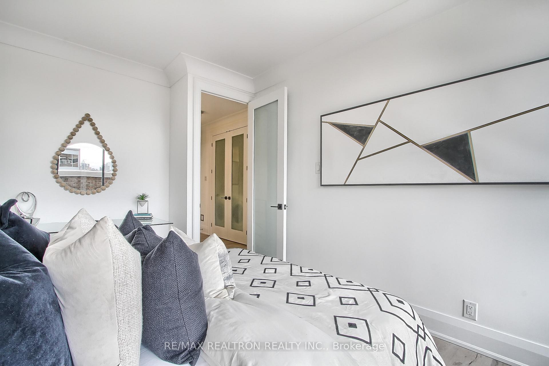 Furnished bedroom with geometric bedding, navy and white pillows, and abstract wall art.
