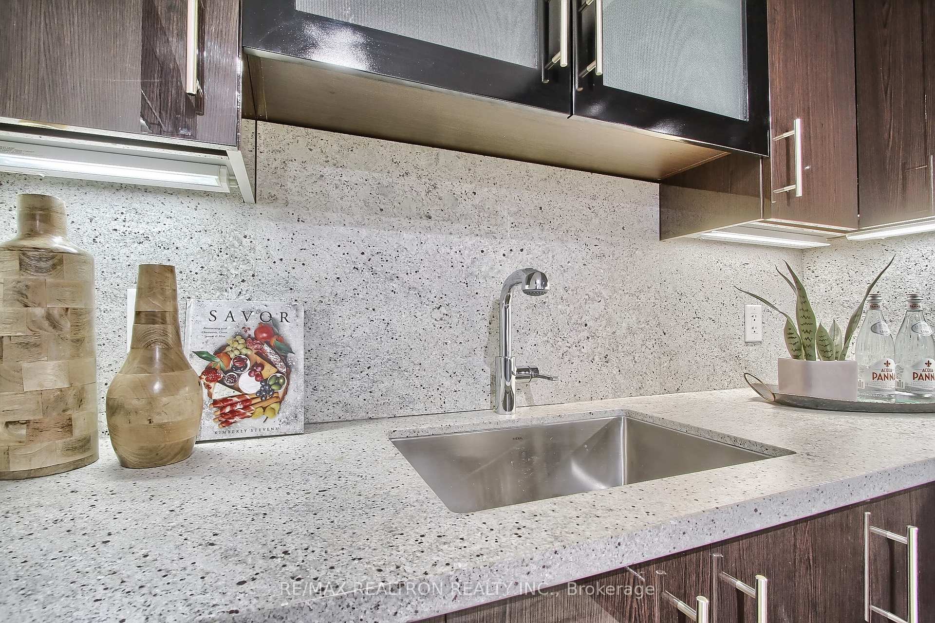 Modern kitchen with dark wood cabinets, speckled stone counters, and an undermount stainless-steel sink.