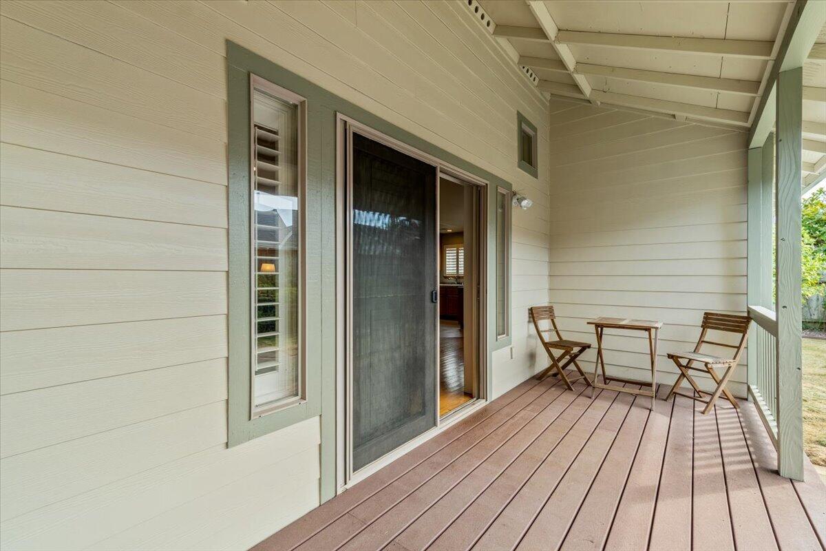 Covered porch with a wood deck, sliding screen door, and a small table with two chairs.