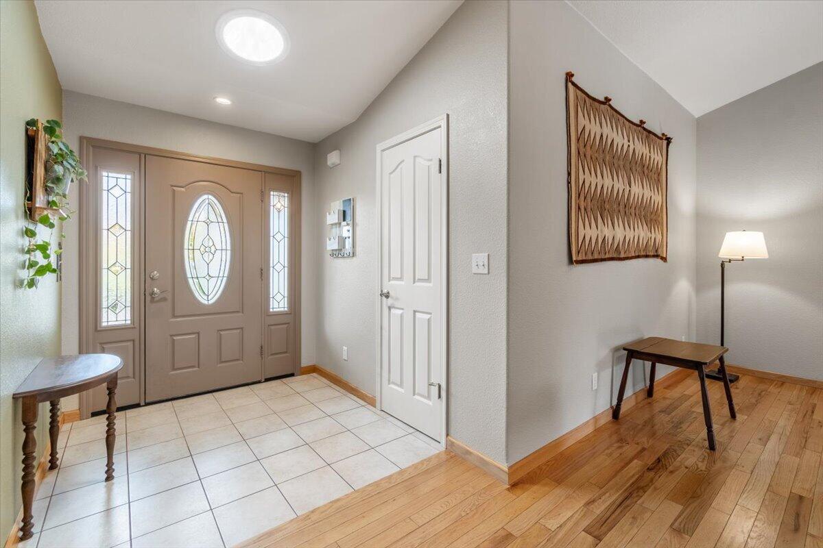Entry foyer with a stained-glass front door, tiled floor, and adjoining hardwood sitting area.