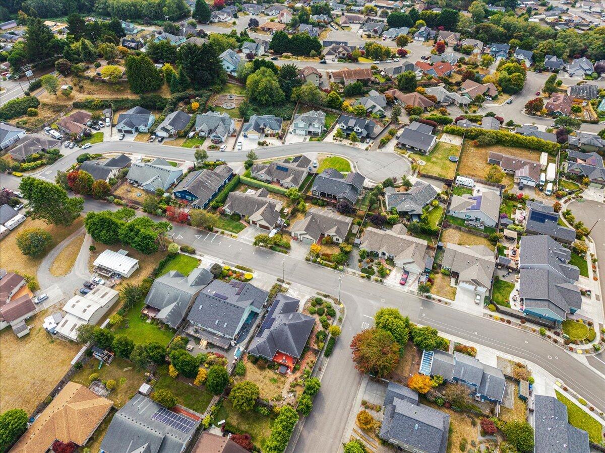 Aerial view of a residential neighborhood with detached homes, tree-lined lots, and a cul-de-sac.
