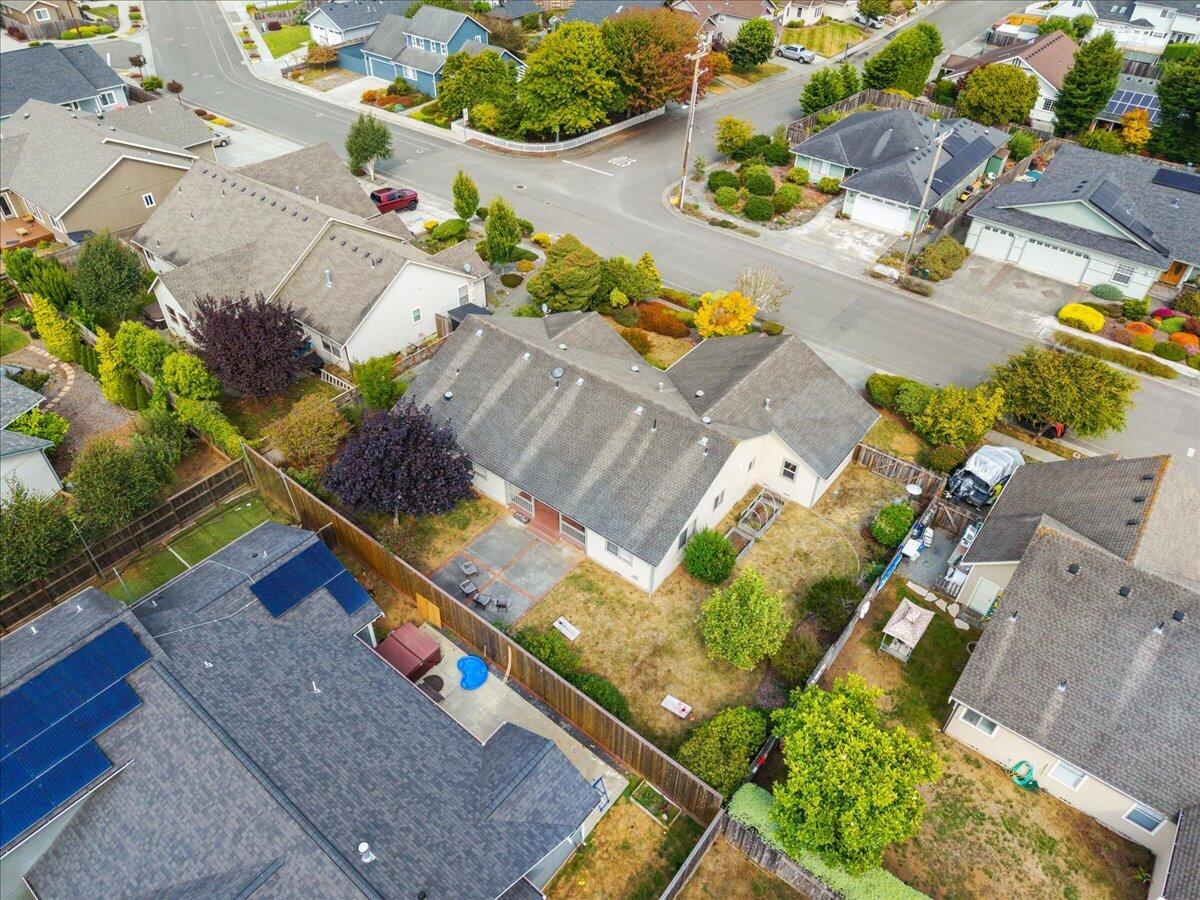 Aerial view of a home with a fenced backyard among tree-lined residential streets.