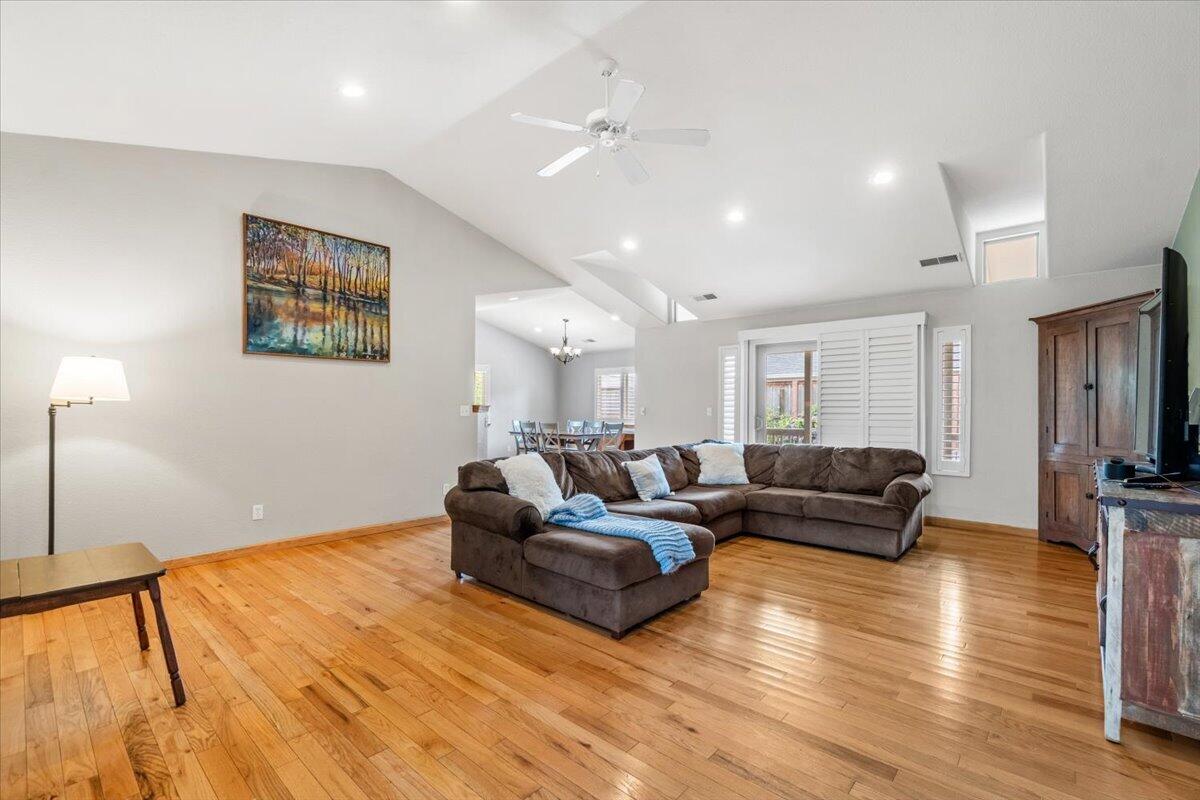 Living room with vaulted ceiling, hardwood floors, and a large brown sectional sofa.