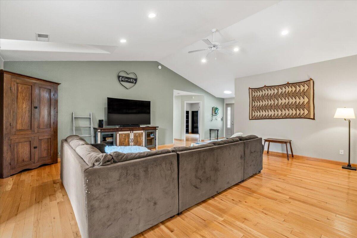 Living room with a large gray sectional, vaulted ceiling, and warm hardwood floors.