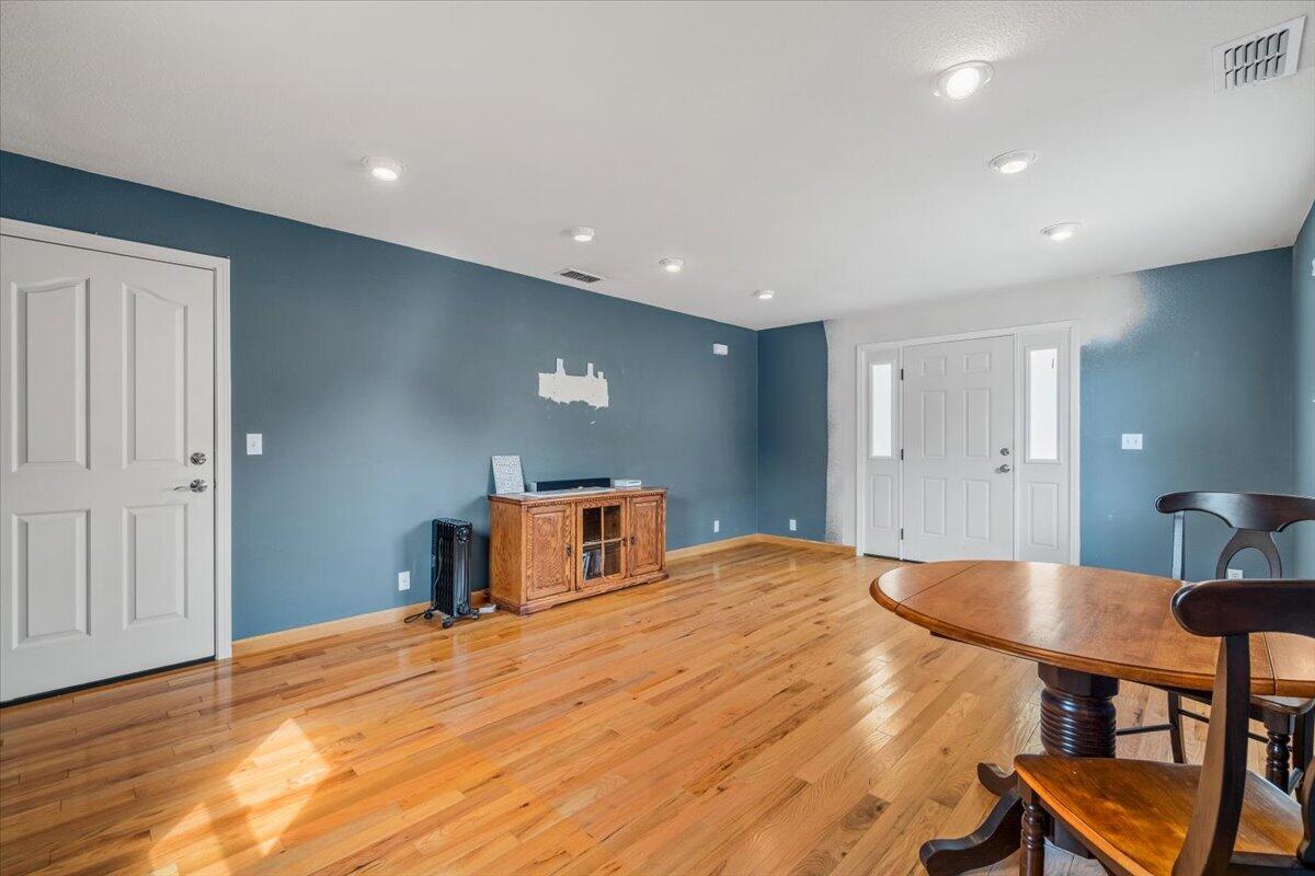 Dining room with blue walls, polished hardwood floors, and a wooden table beside the front entry.