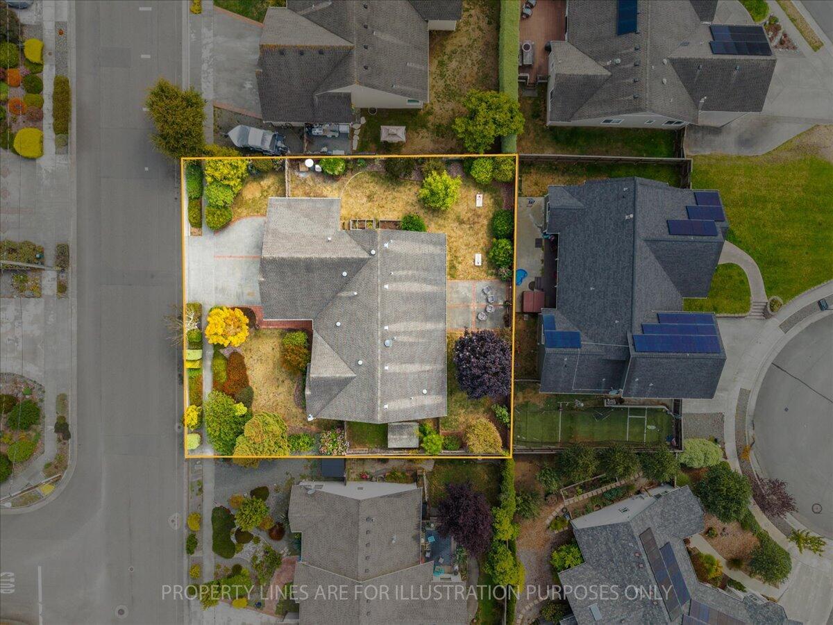 Aerial view of a house and landscaped lot outlined in yellow among neighboring homes.