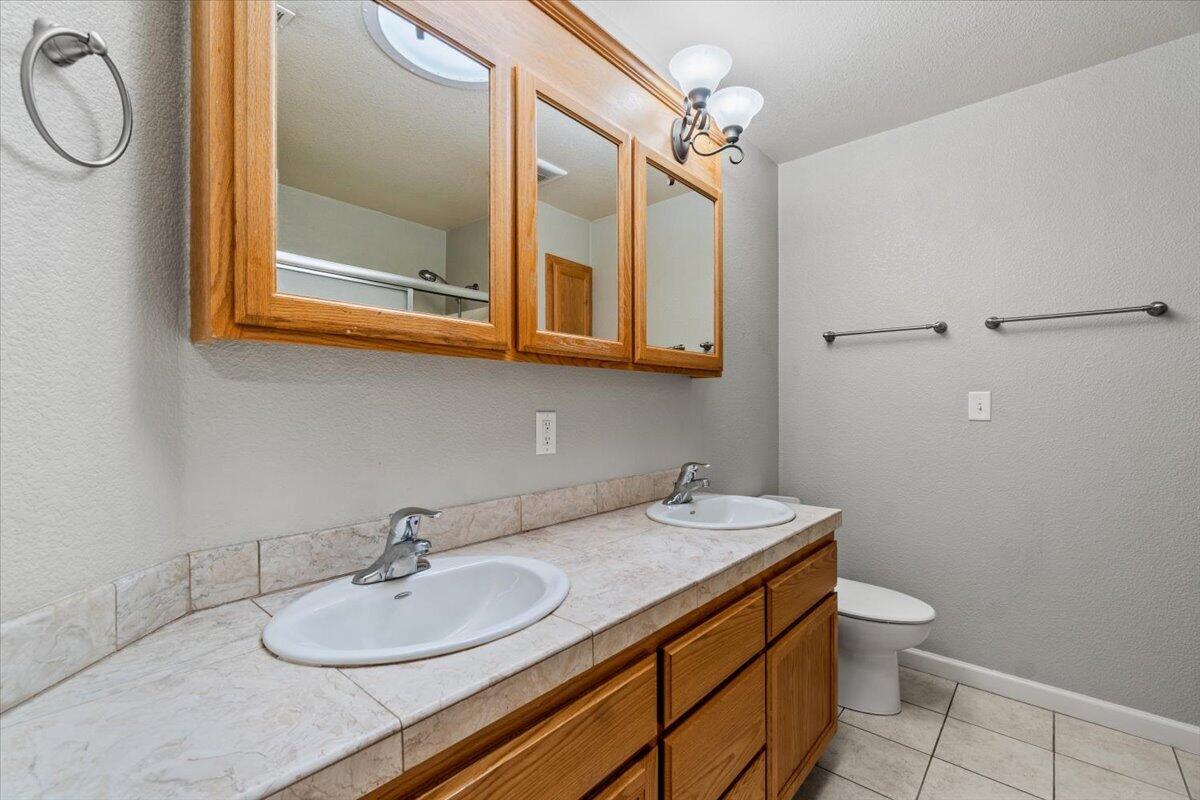 Bathroom with a double-sink tiled vanity, wood cabinets, and mirrored medicine cabinets.