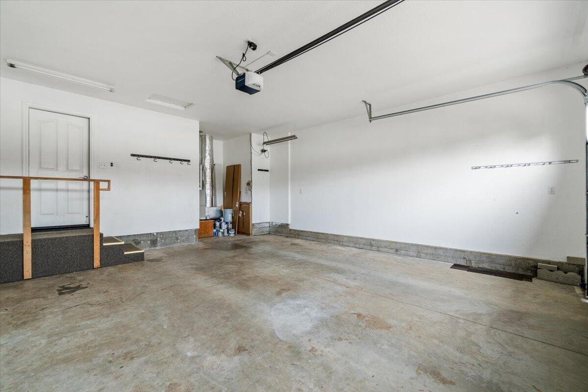 Mostly empty garage with a concrete floor and raised entry landing.
