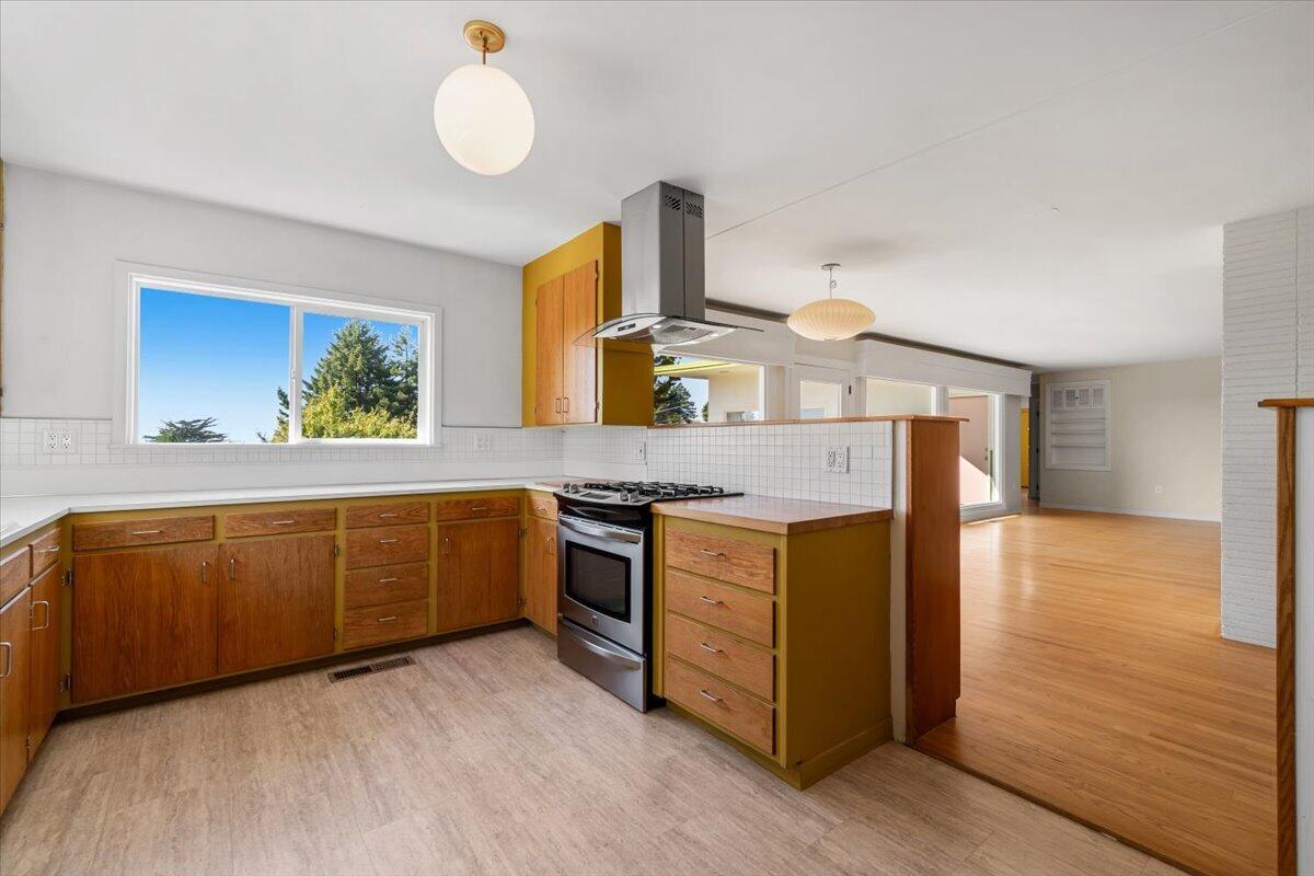 Kitchen with warm wood cabinets, a gas range, and a peninsula opening to the living area.