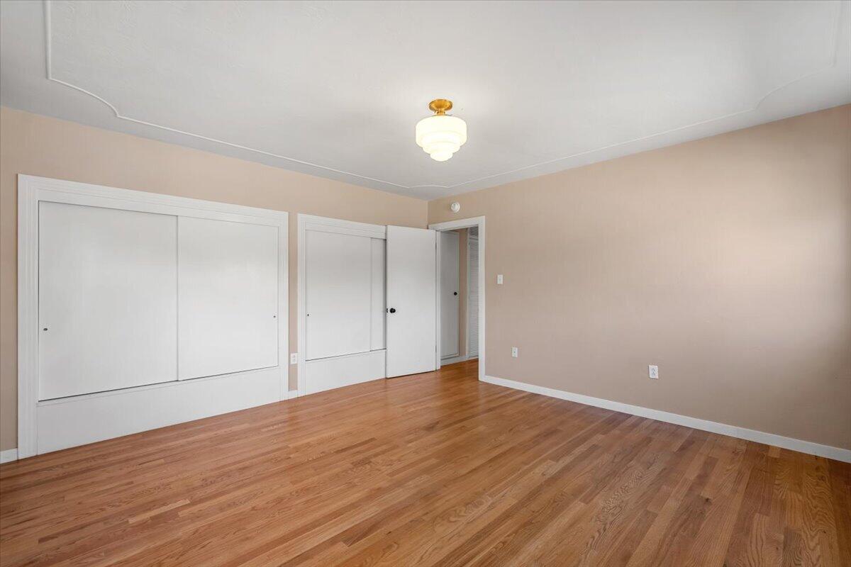 Empty bedroom with hardwood floors and white built-in closets.