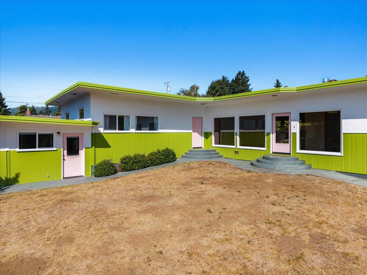 Modern lime-green and white home with pink doors and curved concrete entry steps.
