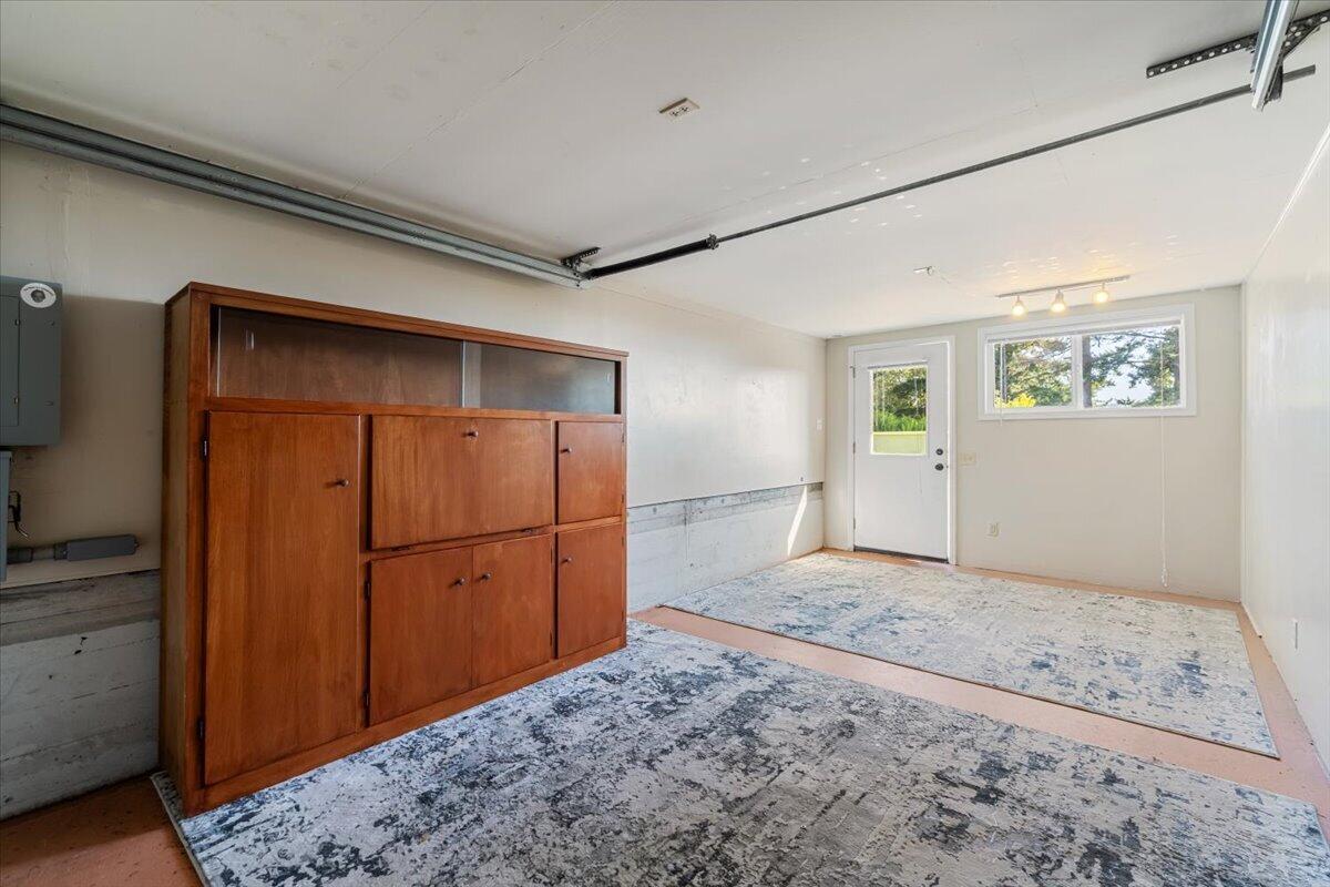 Garage with a large wooden storage cabinet, patterned floor rugs, and a side door with windows.