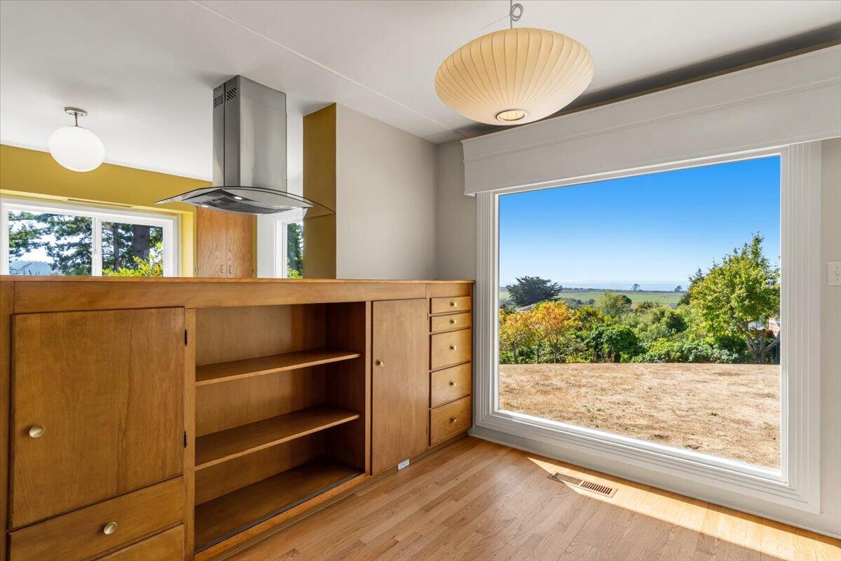 Kitchen with warm wood cabinetry and a large window overlooking greenery and distant water.