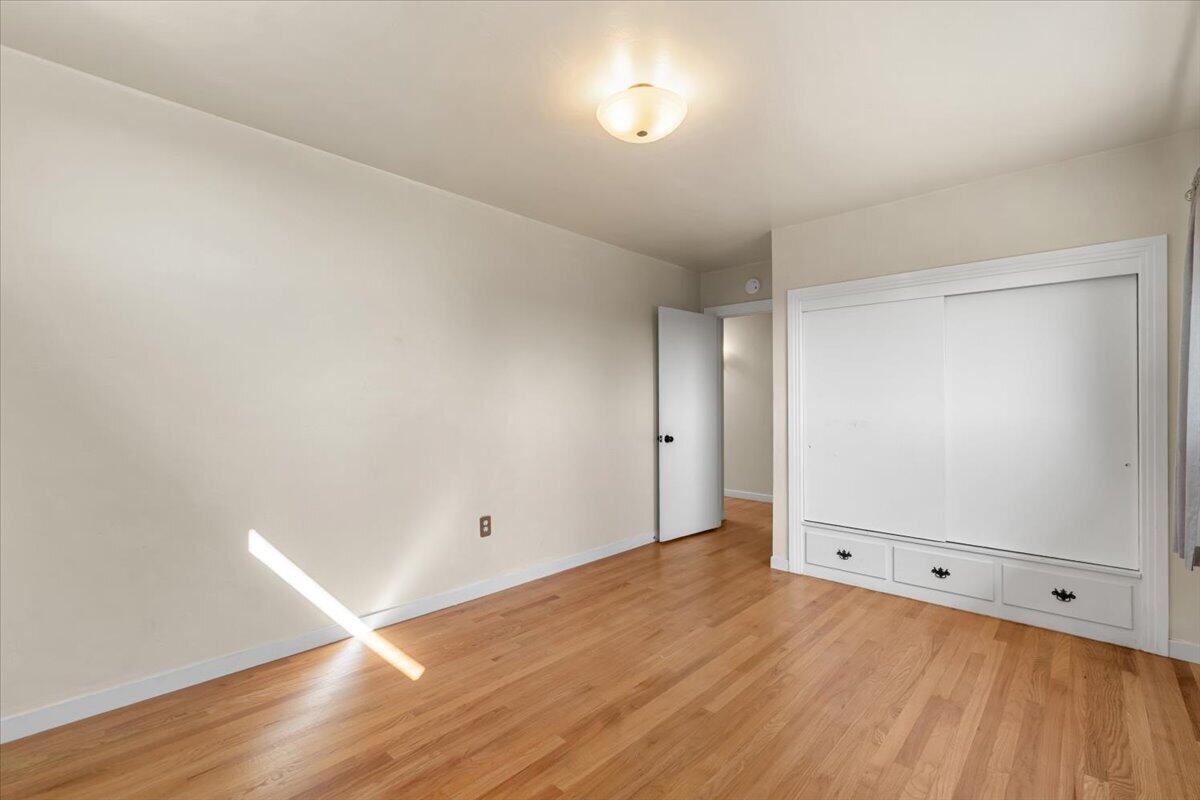 Vacant bedroom with hardwood floors and a large built-in closet with drawers.