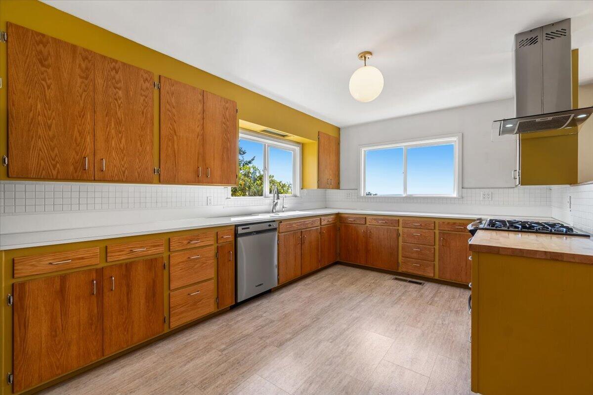 Kitchen with warm wood cabinetry, white tile backsplash, and a peninsula cooktop.