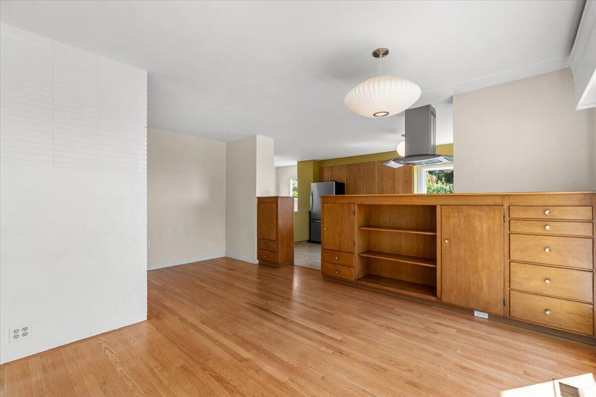 Open kitchen with warm wood cabinetry, built-in shelving, and hardwood floors.