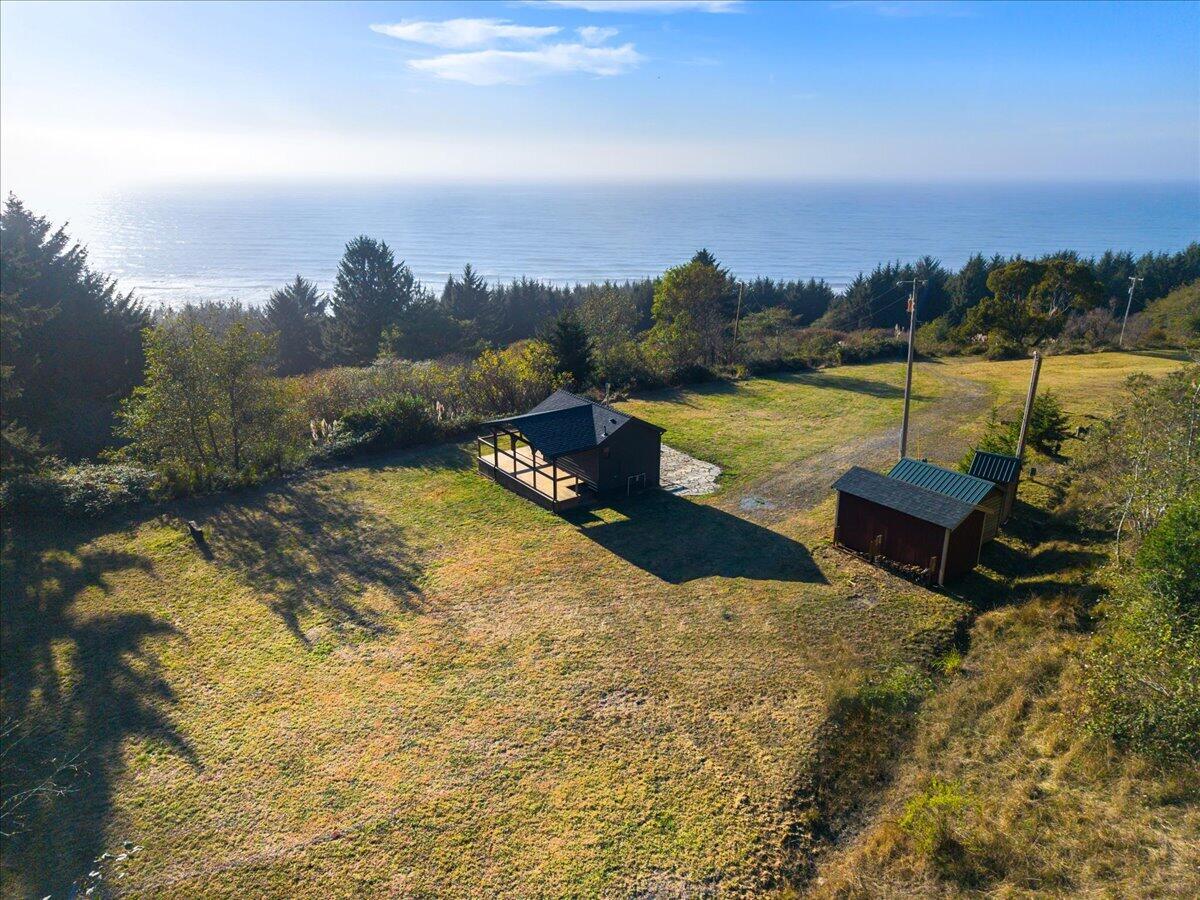 Grassy property with small outbuildings overlooking the ocean.