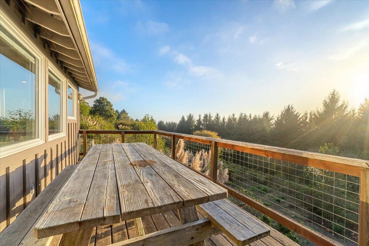 Wooden deck with a picnic table overlooking trees in warm evening sunlight.