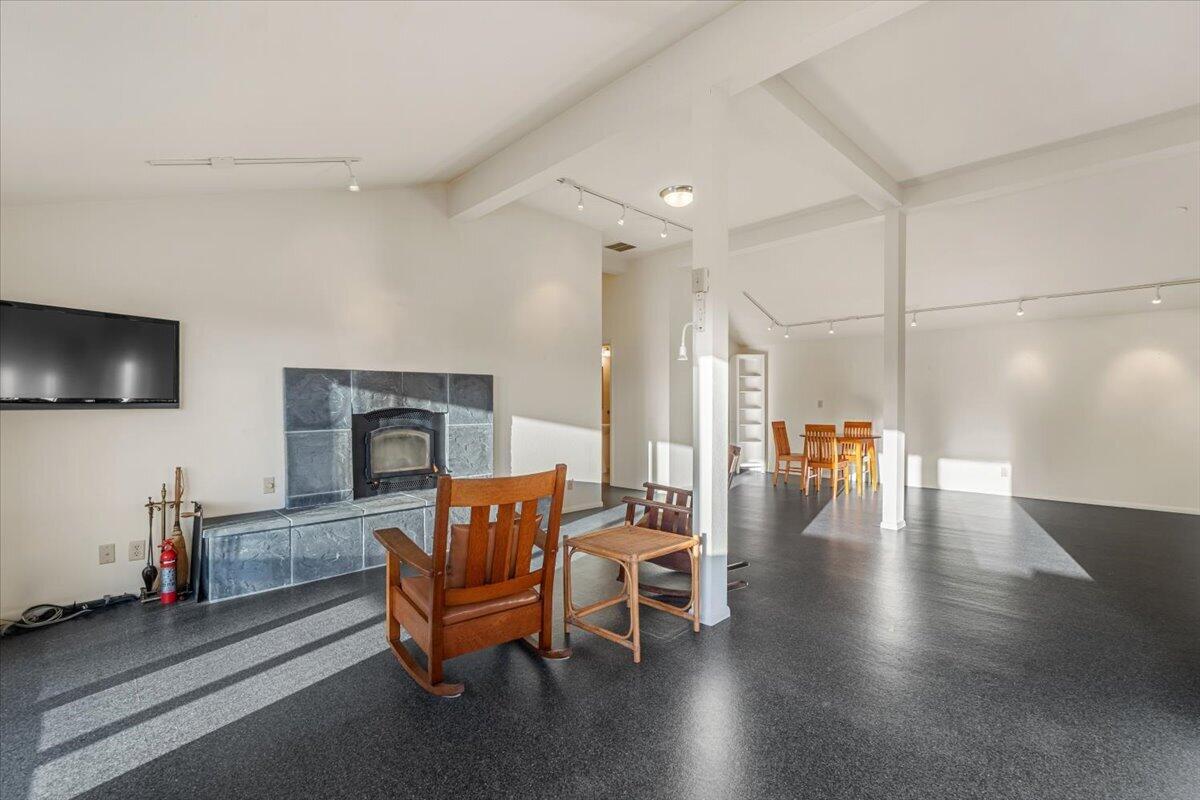 Open living and dining area with a slate fireplace, wooden rocking chairs, and vaulted ceiling.