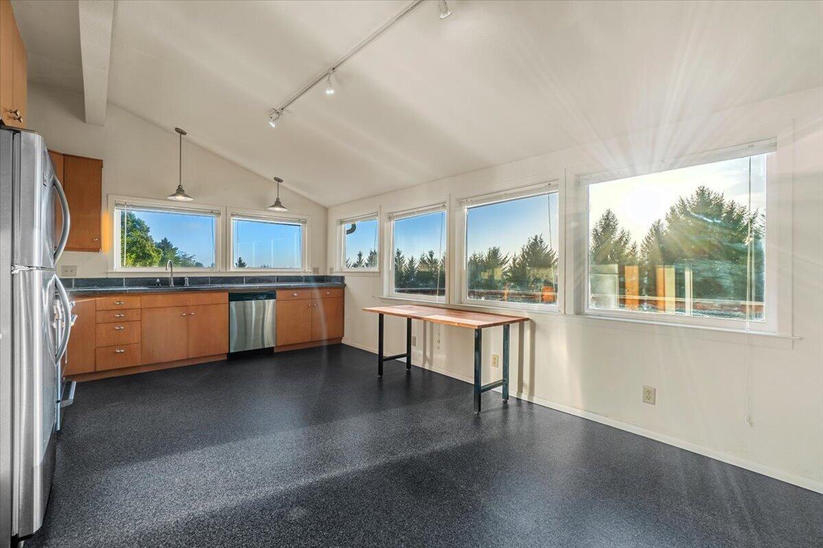 Bright kitchen with wood cabinets, stainless steel appliances, and large windows overlooking trees.