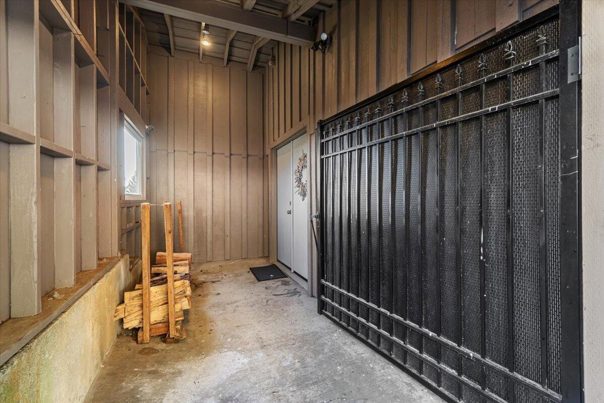 Wood-paneled entry with a large black metal security gate and stacked firewood.