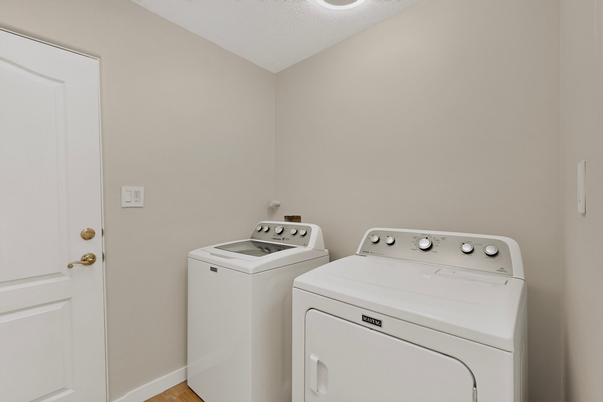 Laundry room with a white top-load washer and Maytag dryer.