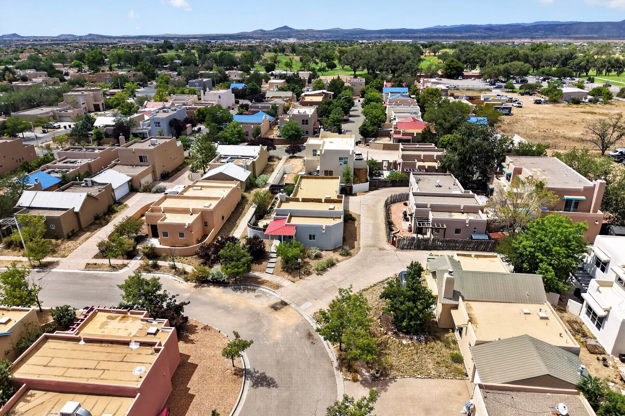 Aerial view of Santa Fe homes along a curving street, with mountains on the horizon.