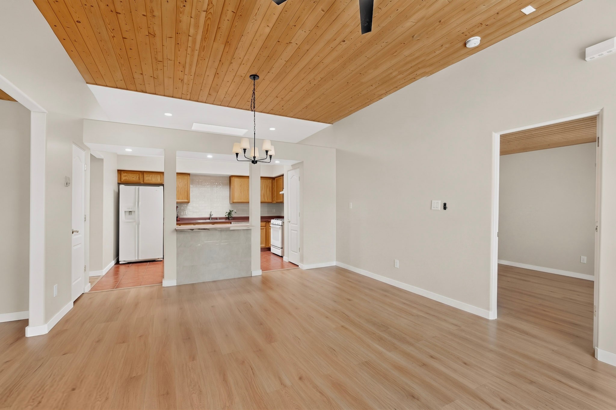 Open dining and living area with a vaulted wood-plank ceiling and kitchen breakfast bar.