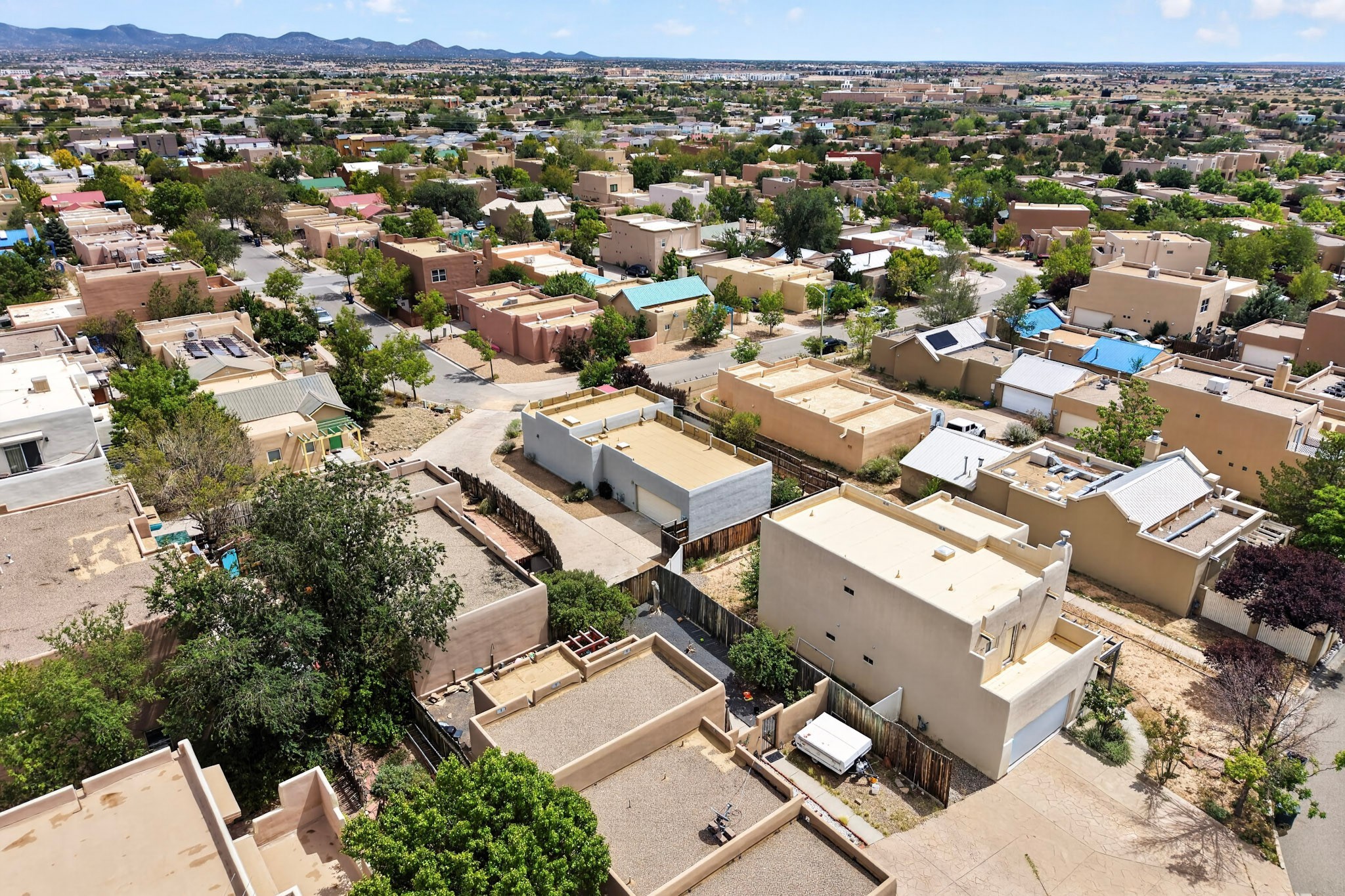 Aerial view of Santa Fe neighborhood with flat-roofed homes and distant mountains.