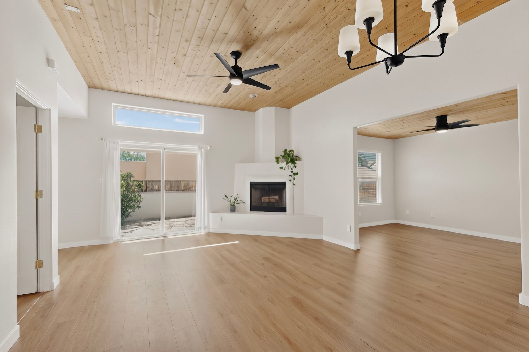 Empty living room with a wood-plank ceiling, fireplace, and sliding glass doors to an enclosed patio.