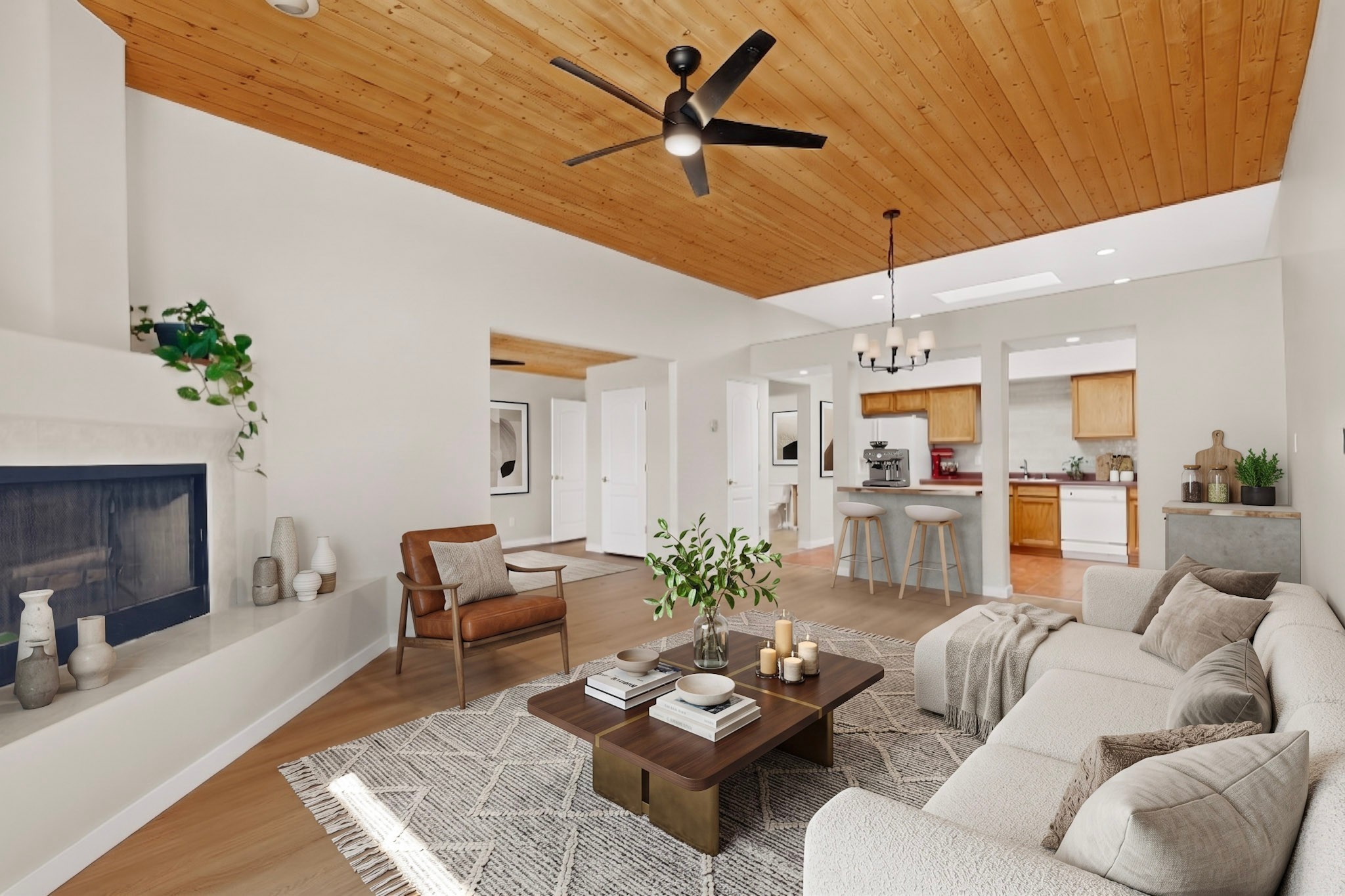 Open-plan living room with a vaulted wood ceiling, fireplace, and cream sofas beside the kitchen.