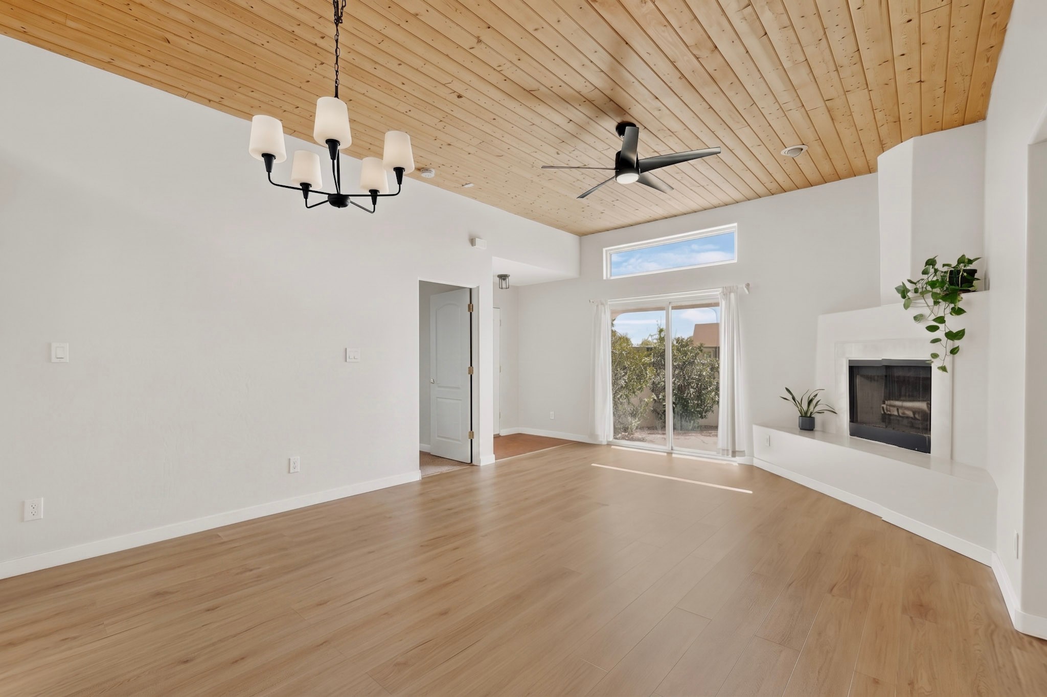 Living room with a wood plank ceiling, white fireplace, and sliding glass doors.