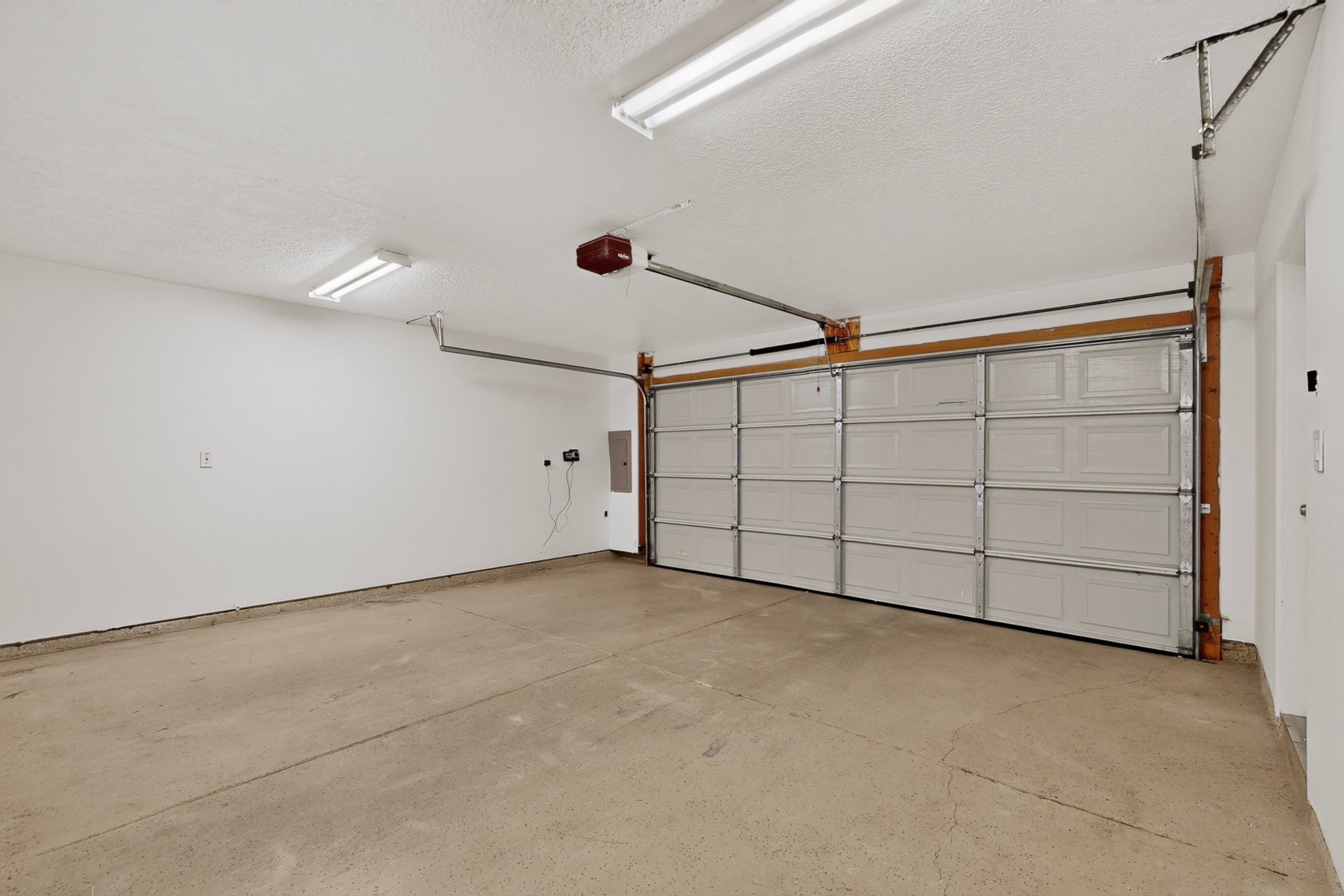 Empty garage with a cracked concrete floor and closed sectional garage door.