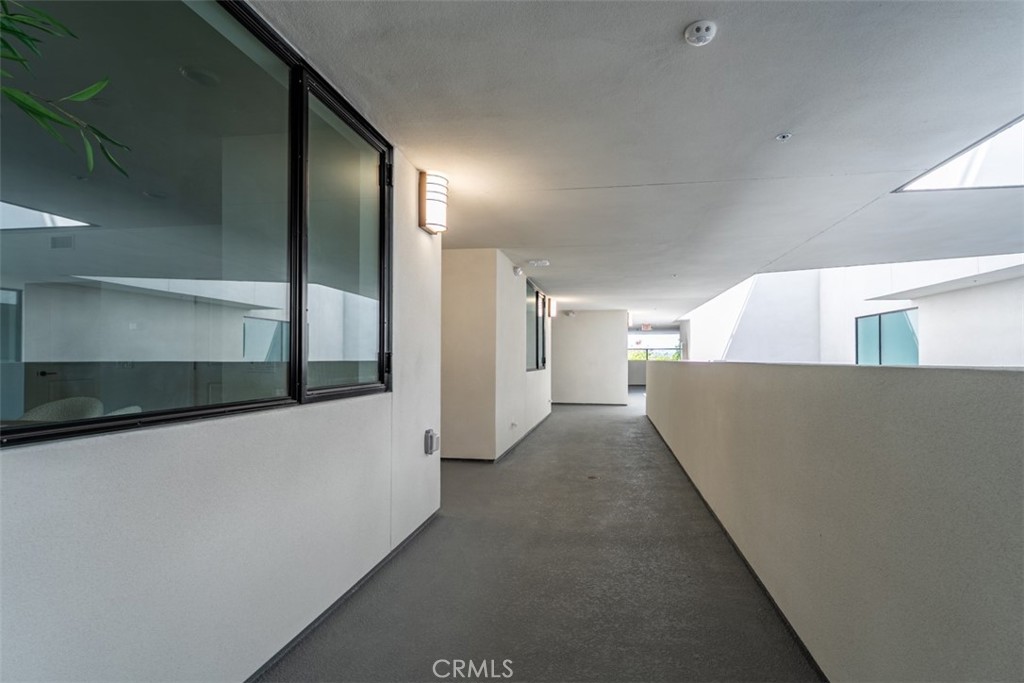 Covered corridor with dark-framed windows and a low parapet.