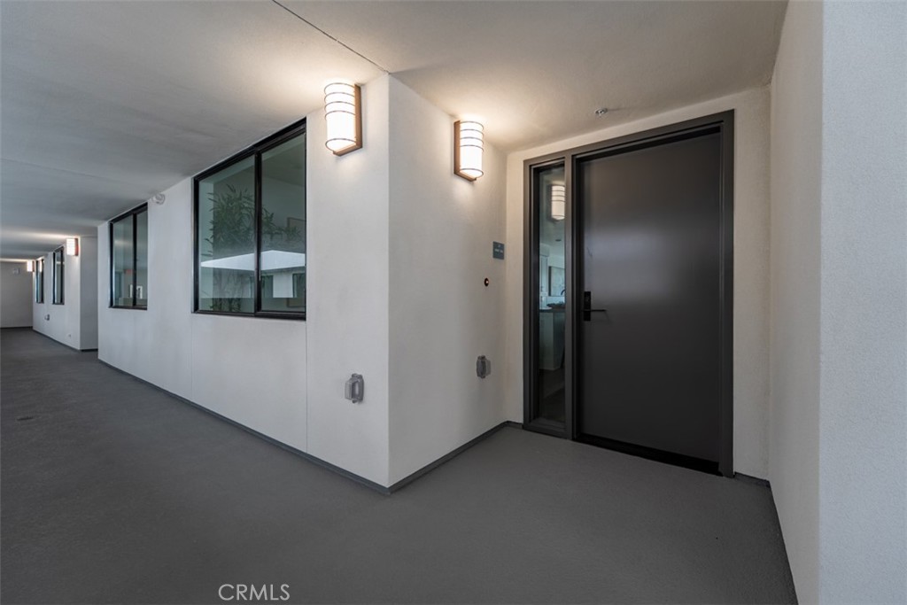 Condominium entry with a dark door, narrow sidelight, and windows along the hallway.