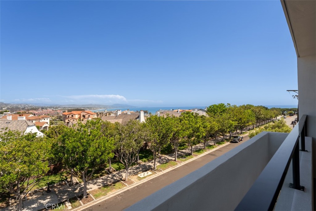 Balcony view over tree-lined streets and homes toward the ocean.