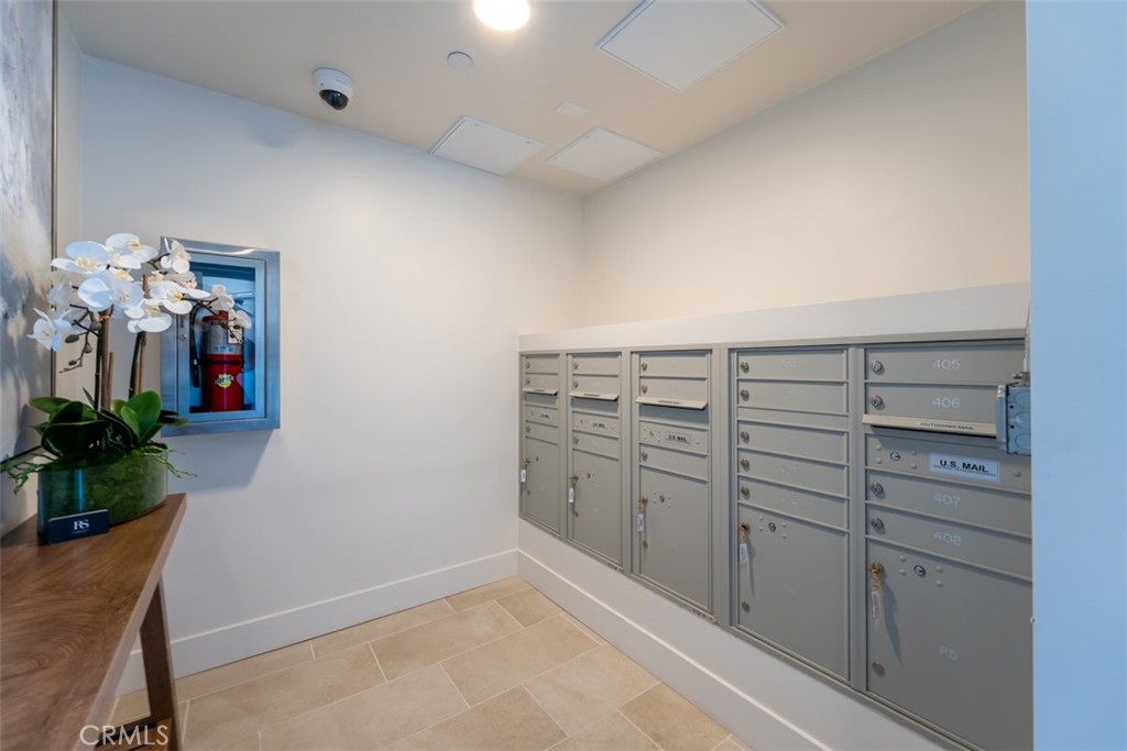 Condominium mailroom with gray mailboxes, a wooden console table, and a potted orchid.